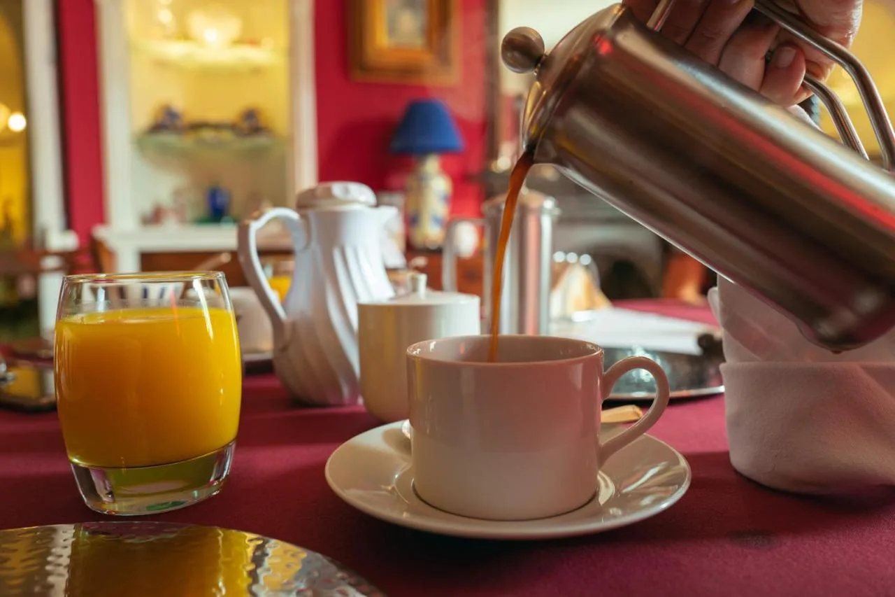 a person is pouring coffee into a cup on a table at Grosvenor Villa in Bath