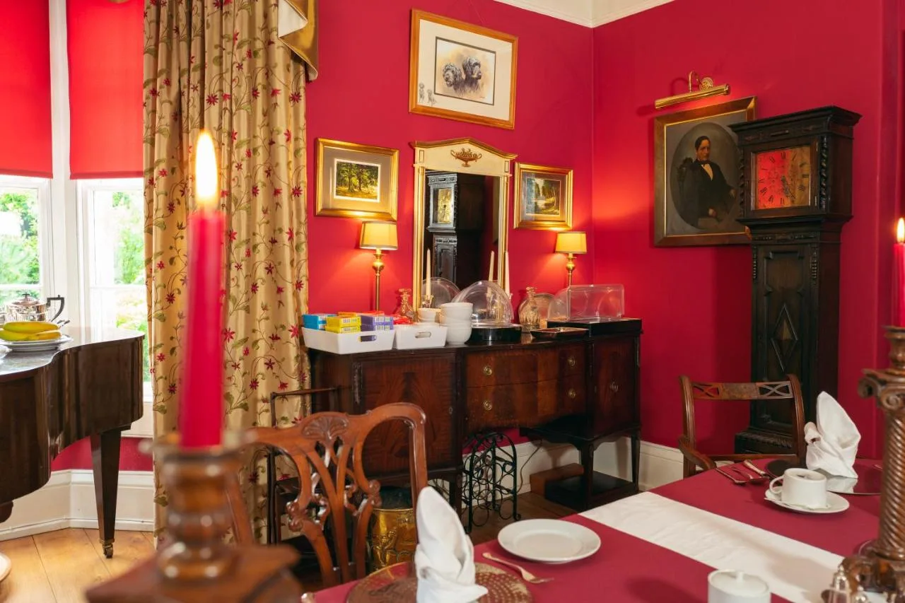 a dining room with red walls and a table and a mirror at Grosvenor Villa in Bath